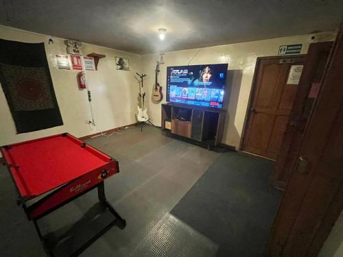 Cette chambre dispose d'une table de ping-pong rouge et d'une télévision. dans l'établissement Intihuatana Hostel, à Pisac