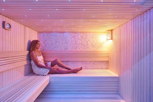 a woman is sitting in a sauna at Neo Hotel Linde Esslingen in Esslingen