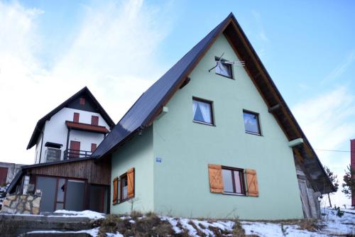 una casa blanca con techo de gambrel en Brano, en Kupres