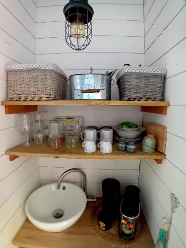 une salle de bain avec un lavabo et des étagères avec des casseroles et des poêles dans l'établissement La Cabane Bordeaux St Augustin, à Mérignac