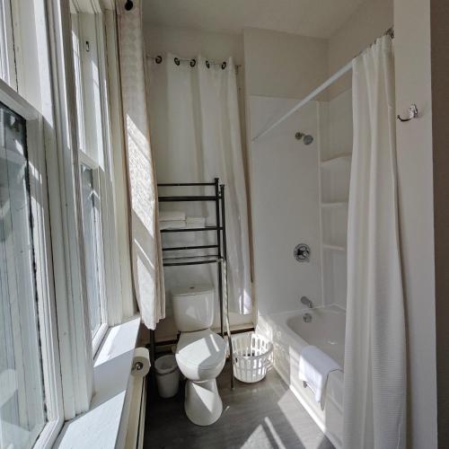 a white bathroom with a toilet and a bath tub at Andy's Blue House in Charlottetown