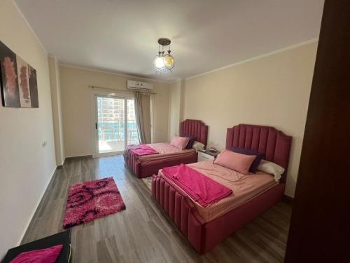 two beds in a room with pink sheets at DOWN Town New El Almain Qrm in Ad Darāzīyah