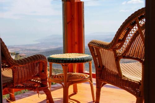 two wicker chairs and a table in front of a window at לוין נוף מרהיב in Amirim