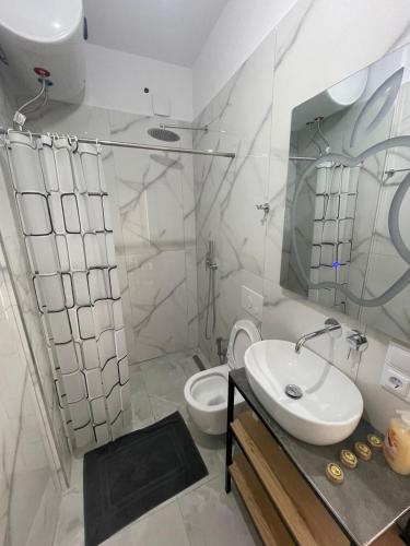a white bathroom with a sink and a toilet at Vanesa Rooms in Sarandë