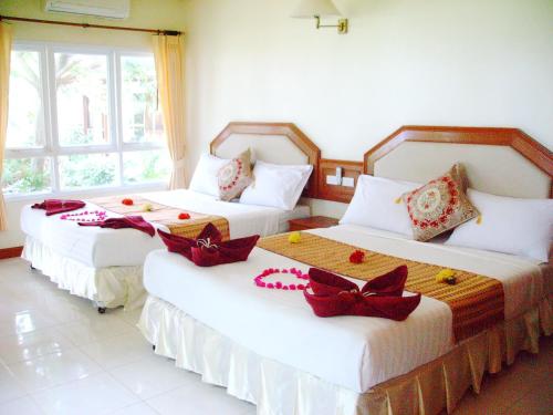 two beds in a hotel room with bows on them at Lanta Palm Beach Resort Krabi , Koh Lanta - SHA Plus in Ko Lanta