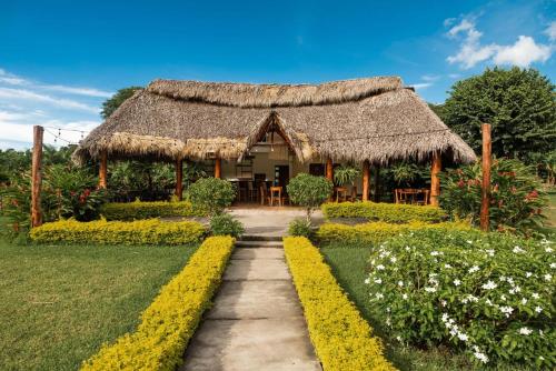a house with a thatched roof and a path at Hotel Boutique Victoria in Moyogalpa