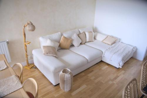 un salon avec un canapé blanc avec des oreillers dans l'établissement Appartement Moderne et Spacieux, à Créteil