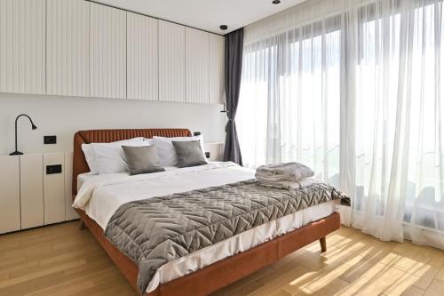 a bedroom with a large bed and large windows at Belgrade City Escape - Genex in Belgrade
