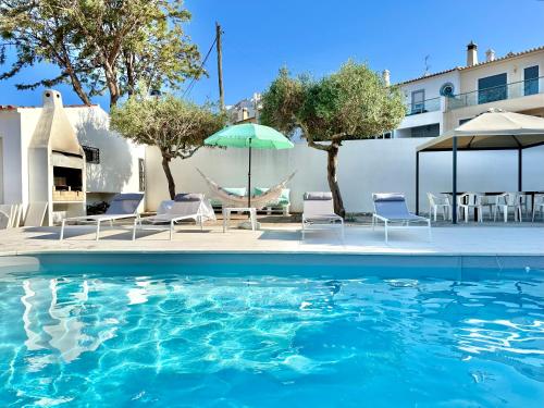 a pool with chairs and umbrellas next to a building at Casa dos Trevos, 5 Bedroom Villa with Pool in Lagos