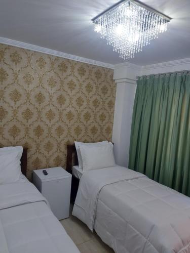 1 dormitorio con 2 camas y lámpara de araña en Casa Amarela Pousada, en Domingos Martins