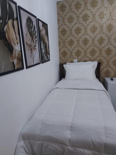 un letto in una stanza con tre immagini sul muro di Casa Amarela Pousada a Domingos Martins