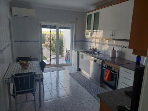 a kitchen with white cabinets and a table with a tableablish at Vivenda Cordeiro in Bárrio