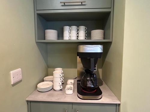 a coffee maker in a cupboard with plates and cups at Hamilton Court Hotel Hoole in Chester