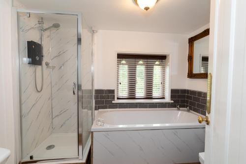 een badkamer met een bad en een glazen douche bij Coalbrookdale Villa in Ironbridge