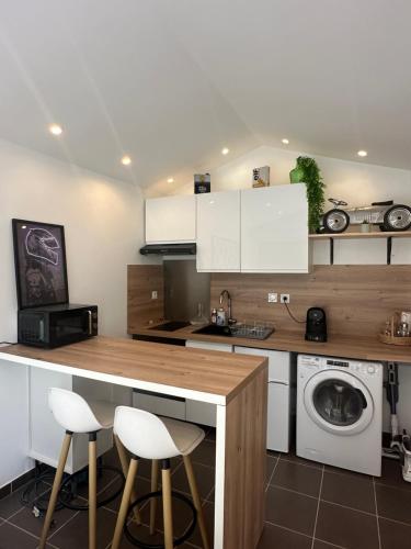 une cuisine avec des armoires blanches et une laveuse et une sécheuse dans l'établissement Studio Le Mans, au Mans