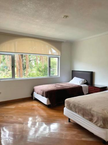 1 dormitorio con 2 camas y ventana grande en Departamento Amplio En El Centro De Otavalo en Otavalo