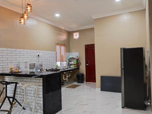 a kitchen with a black refrigerator and a counter at Villa Adeeva Homestay Langkawi in Pantai Cenang