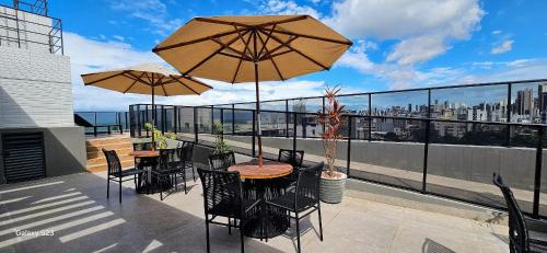 two tables and chairs with umbrellas on a balcony at Flats Tramonto - By EasyHost in João Pessoa