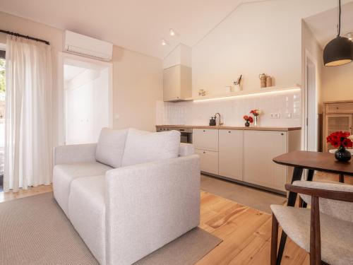 a living room with a white chair and a kitchen at Quinta da Casa Grande in Ponta Delgada