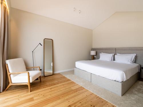 a bedroom with a white bed and a chair at Quinta da Casa Grande in Ponta Delgada