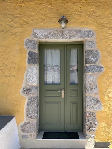 a green door in a stone building with a light above it at Alexander House 2 in Leonidion
