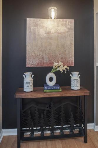 a table with two vases and a painting on a wall at THE ULTIMATE SMOKY MOUNTAIN ESCAPE! Game Room, Theater, Hot Tub, Fire Pit & the Ultimate in Luxury Living - Close to All Major Top Attractions in Pigeon Forge