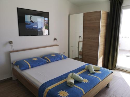um quarto com uma cama com lençóis azuis e uma televisão em Apartments Martin em Primošten