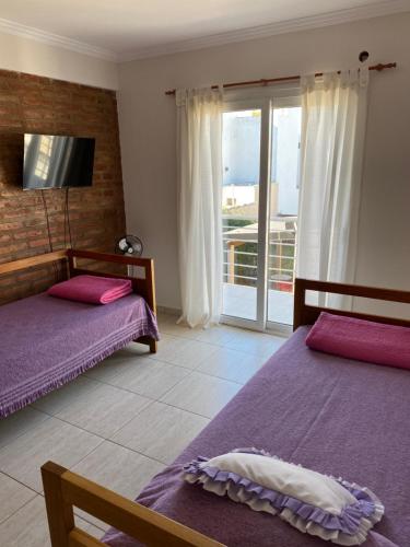 ein Schlafzimmer mit zwei Betten und einem Balkon in der Unterkunft Complejo Pampa in Santa Rosa