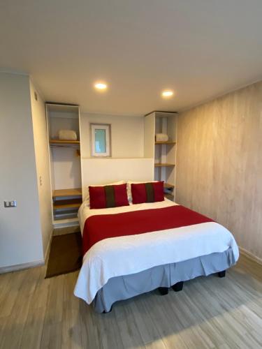 ein Schlafzimmer mit einem großen Bett mit roten Kissen in der Unterkunft ApartHotel Kintumay in Puerto Varas
