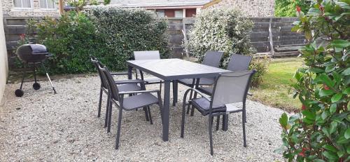 a table with chairs and a grill in a garden at Maison de village in Sadroc
