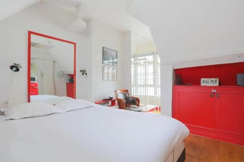 - une chambre avec un lit blanc et une commode rouge dans l'établissement Cosy flat Saint-Michel - Seine, à Paris