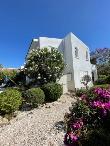 una casa blanca con flores delante en Coral Bay Villa Daniella, en Bahía de Coral