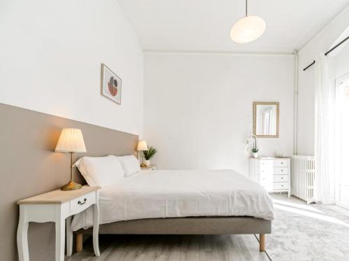 a white bedroom with a bed and a lamp at Villa Vichéia - Appartement 2 in Vichy