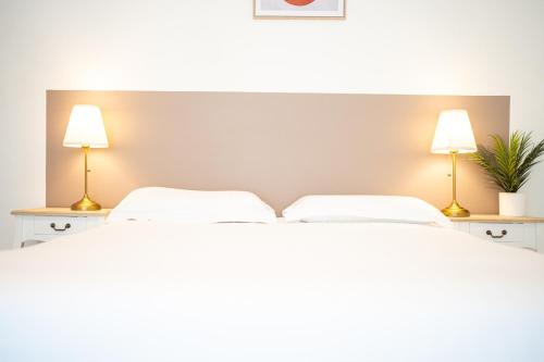 a bedroom with two white beds and two lamps at Villa Vichéia - Appartement 2 in Vichy