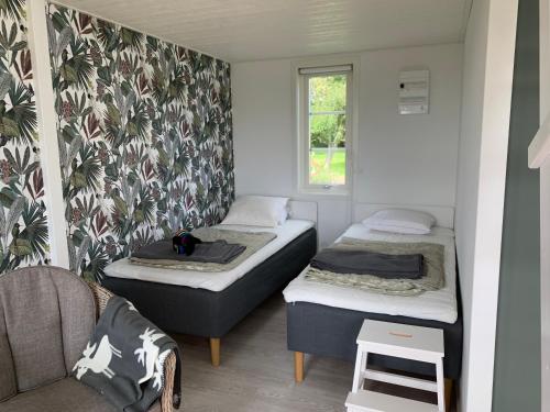 ein Zimmer mit zwei Betten, einem Stuhl und einem Fenster in der Unterkunft Hassels hus in Vikingstad