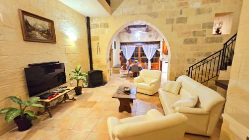 a living room with white couches and a tv at Traditional Farmhouse Central Gozo in Xagħra
