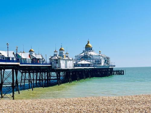a pier with buildings on the beach next to the ocean at "The Parlour" Seafront Apartment in Eastbourne