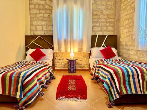 a room with two beds and a red rug at QUIET OASIS Luxury Stone Villa with Panoramic Views near Essaouira in Essaouira