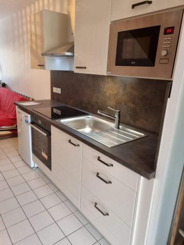 une cuisine avec un évier et un micro-ondes dans l'établissement Eléonore, F2 en duplex avec cour commune et proche de la mer, 3, à Ver-sur-Mer