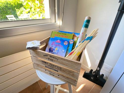 a wooden basket with books and books on a stool at Maison Trezma à 450m de la plage in Plonévez-Porzay