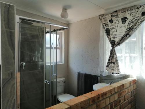 uma casa de banho com um chuveiro, um WC e uma janela. em Charlie's Spot - Norwood em Joanesburgo