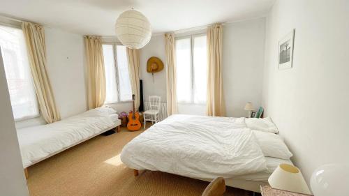 - une chambre avec 2 lits et une guitare dans l'établissement Charmante Maison de Pêcheur à Trouville sur Mer, à Trouville-sur-Mer