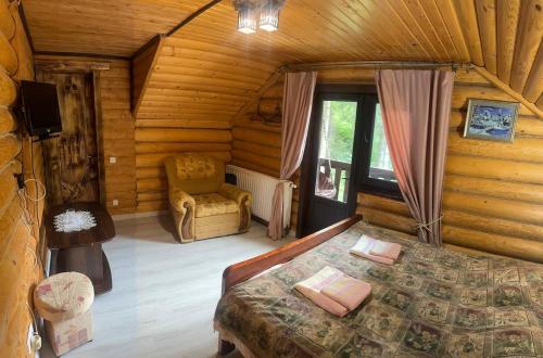 una camera da letto in una baita di tronchi con un letto e una sedia di Верховинський водограй a Synevyrsʼka Polyana