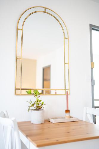 un miroir en laiton au-dessus d'une table en bois avec une plante dessus dans l'établissement Villa Vichéia - Appartement 33, à Vichy