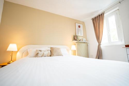 a bedroom with a large white bed and a window at Villa Vichéia - Appartement 33 in Vichy
