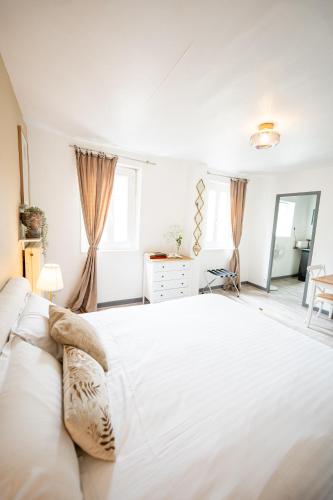 une chambre blanche avec un grand lit et un miroir dans l'établissement Villa Vichéia - Appartement 33, à Vichy