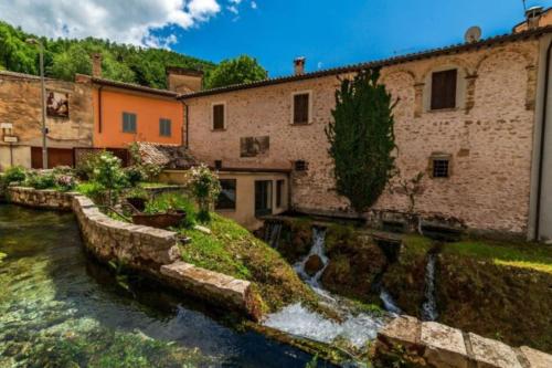 a house with a river in front of a building at Casa Vacanze Fonte del Menotre in Foligno