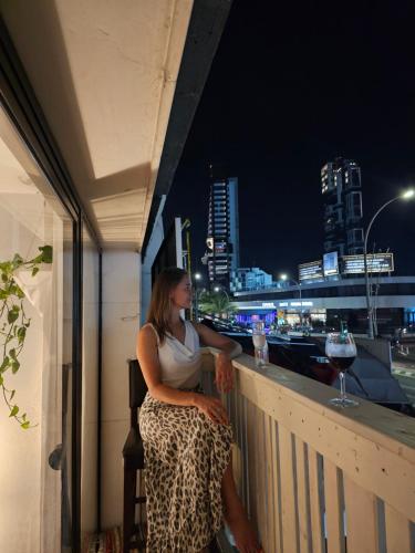 a woman sitting on the ledge of a balcony at night at Touristarea Sea&City Lifestyle studio in Limassol