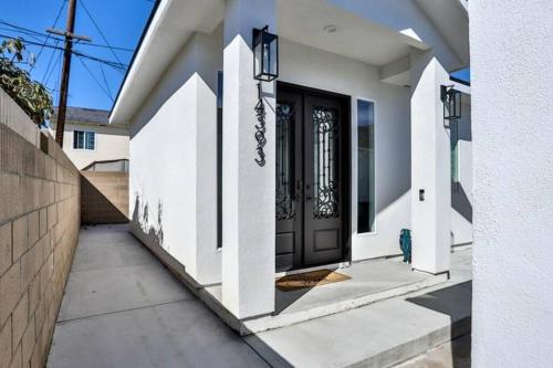 a white house with a black door and stairs at H&H New Built 2023 Hidden Gem Heart of OC 3 Queen Beds in Westminster