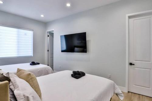 a bedroom with two beds and a tv on the wall at H&H New Built 2023 Hidden Gem Heart of OC 3 Queen Beds in Westminster